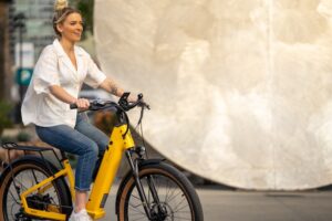 Kobieta na pomarańczowym rowerze elektrycznym podczas jazdy po mieście